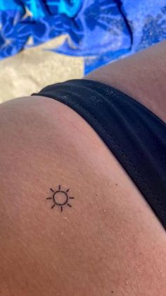 a woman with a small sun tattoo on her lower back side ribcacture