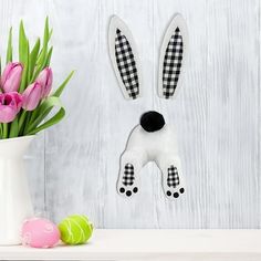 a vase filled with pink tulips next to a paper cutout of a dog