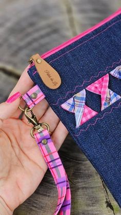 a hand holding a pink and blue purse