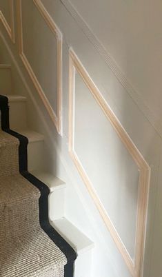 the cat is sitting on the carpeted stair case next to the bannister