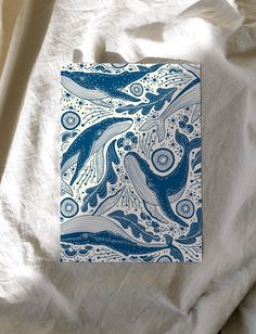 a blue and white print on a white sheet that is laying on top of a bed