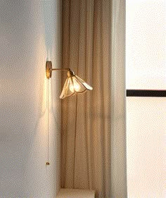 a light that is on the side of a wall next to a window with curtains