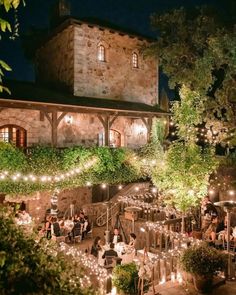 an outdoor venue with string lights and people sitting at the tables in front of it