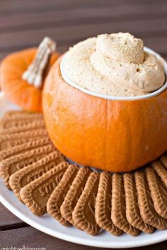 a plate topped with an orange and some crackers next to a bowl of whipped cream