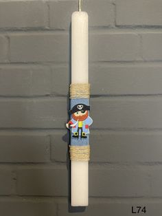 a white candle with a pirate on it hanging from the side of a brick wall