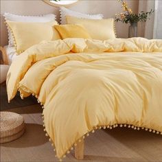 a yellow comforter with pom - poms on the bottom is in front of a mirror