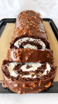 there is a chocolate roll with white frosting on the top and one slice cut off