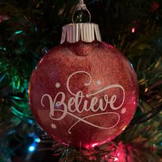 a red ornament with the word believe on it hanging from a christmas tree