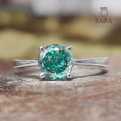 an oval cut green diamond ring on top of a rock