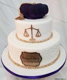 a three tiered cake with a law symbol on the side and a purple pillow on top