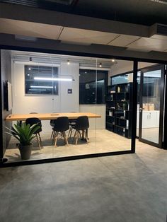 an office with glass walls and tables in the center, surrounded by black chairs on either side