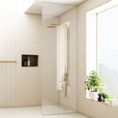 a white bathroom with a large mirror and plants in the window sill next to it