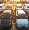 a parking lot filled with lots of white cars next to each other in the sun