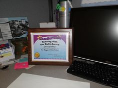 a computer monitor sitting on top of a desk next to a framed poster and keyboard