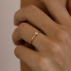 a woman's hand wearing a gold ring with a diamond