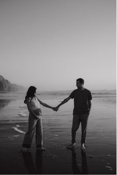 a man and woman holding hands on the beach