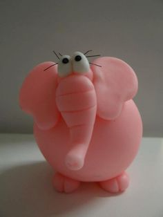 a pink elephant figurine sitting on top of a white table next to a wall