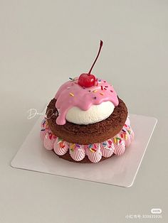 a chocolate cupcake with pink frosting and sprinkles on top, topped with a cherry