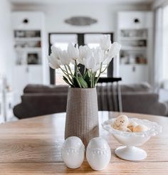 white flowers in a vase and eggs on a table