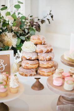 a table topped with lots of donuts covered in frosting next to cakes and cupcakes