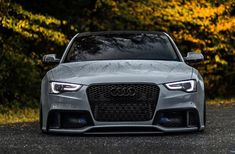 the front end of an audi car with its hood covered in water and trees behind it