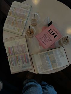 an open book sitting on top of a table next to two cups and a drink