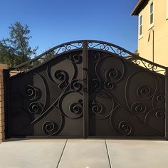 an iron gate is shown in front of a brick wall and fenced driveway area