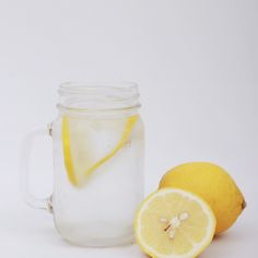 two lemons next to a mason jar filled with water and one has a slice of lemon in it