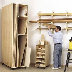 a man standing next to a shelf filled with wooden shelves and boxes on top of it