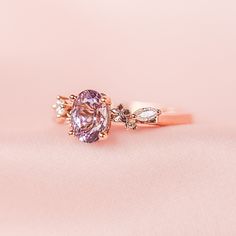 a pink diamond ring sitting on top of a white cloth