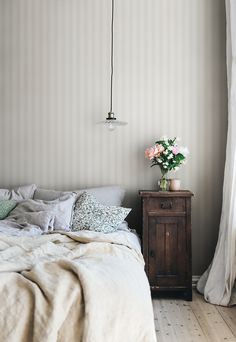 a bedroom with a bed, nightstand and flowers