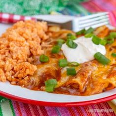 mexican food with rice and green onions on a red and white plate next to a fork