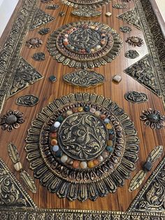 an intricately designed wooden table top with decorative designs on it's sides and gold trimmings