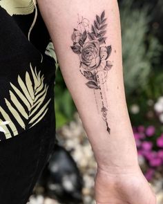 a woman's arm with a rose and arrow tattoo on the left inner forearm