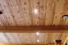 a bed sitting under a wooden ceiling next to a light on a lamp fixture in a bedroom