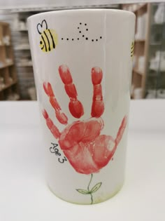 a handprinted coffee cup with a bee on the bottom and red ink in the middle