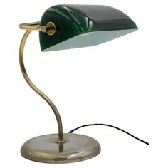 a green and gold desk lamp with a black shade on the top, sitting on a metal base