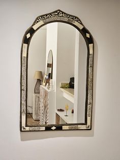 a mirror hanging on the wall above a table with a vase and lamp in it