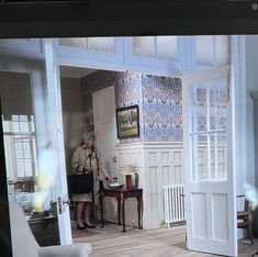 a woman standing in a living room next to a table