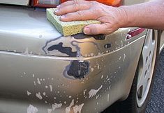 a person cleaning the hood of a car with a sponge