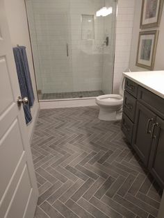 a bathroom with gray and white tile flooring next to a walk - in shower