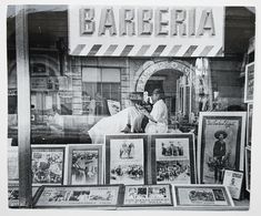 an old black and white photo of people in front of a barbershop with pictures on display