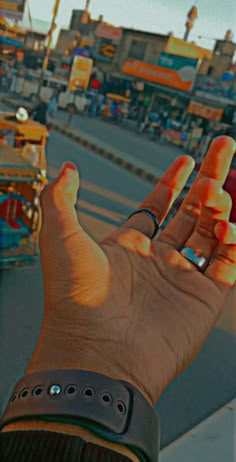 a person holding their cell phone up to the camera in front of an amusement park