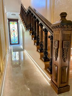 the stairs are made of wood and have decorative railings on each side, along with a stained glass window