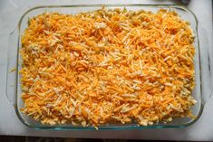 a glass casserole dish filled with shredded cheese