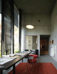 a room with a long table and red chair next to a white refrigerator freezer