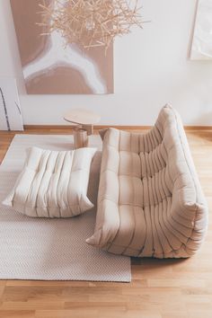 a living room filled with furniture on top of a hard wood floor covered in white rugs