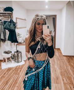 a woman taking a selfie while wearing a fish net top and blue mermaid skirt