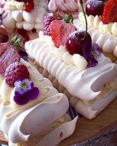 several desserts are arranged on a wooden platter with purple flowers and cherries