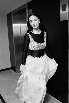 black and white photo of a woman in a long dress posing for the camera with her hands on her hips